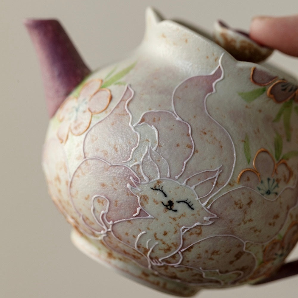 Macro close-up of exquisite hand-drawn fox and floral motifs on SONGKILN gongfu porcelain teapot, contrasting purple spout and handle art detail